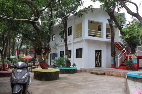 uma scooter estacionada em frente a um edifício branco em Vellankani Resort Gorai em Mumbai