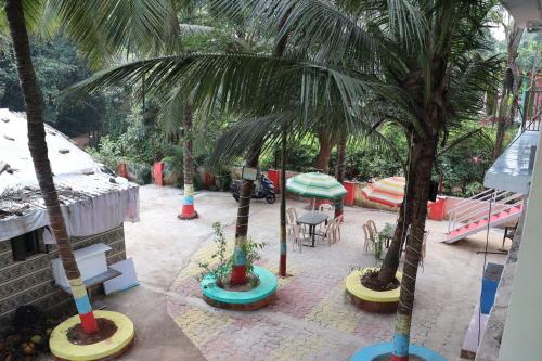 a patio with palm trees and a table and chairs at Vellankani Resort Gorai in Mumbai