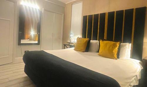 ein Schlafzimmer mit einem großen Bett mit gelben Kissen in der Unterkunft *Luxury 9ine Lush Jacuzzi Apartment & Balcony* in Birmingham