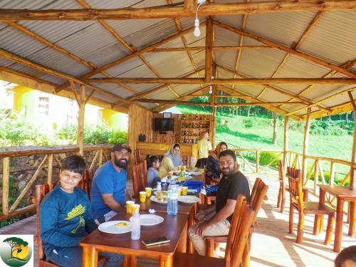 un groupe de personnes assises à une table dans un restaurant dans l'établissement Antique cottages, à Kabale