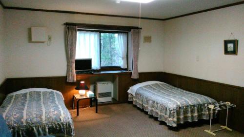 信濃的住宿－ペンションヴォルケ，酒店客房设有两张床和窗户。