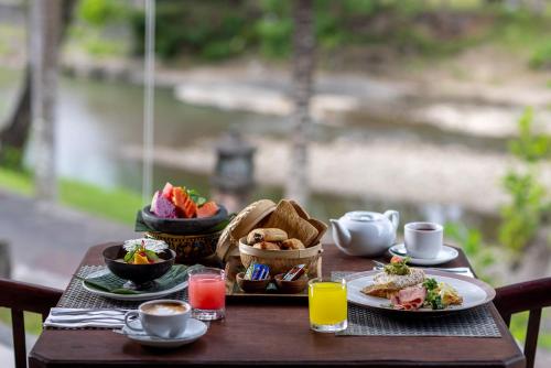 a table with a tray of breakfast food on it at Santi Mandala Villa & Spa in Sukawati