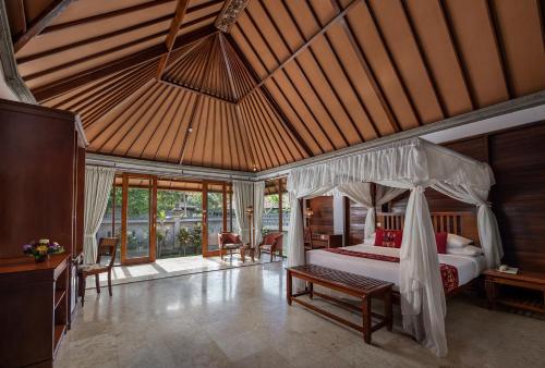 a bedroom with a canopy bed in a room at Santi Mandala Villa & Spa in Sukawati
