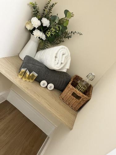 a shelf with towels and a basket and a vase with flowers at Motorpoint view in Nottingham