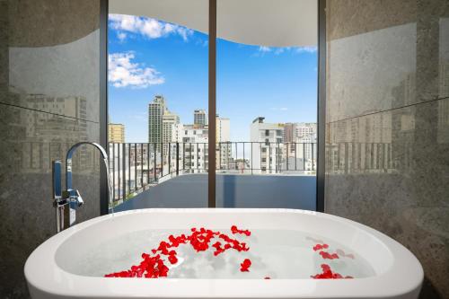 a bathroom with a bath tub filled with red flowers at Golden Lotus Grand in Da Nang