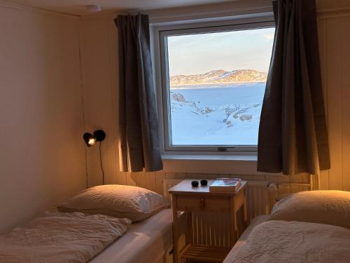 two beds in a room with a large window at Grand seaview house Ilulissat in Ilulissat
