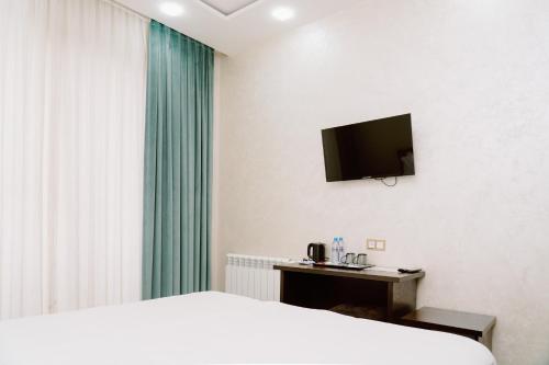 um quarto com uma cama e uma televisão na parede em PGA Hotel Free Shuttle to Airport em Tashkent