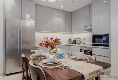 a kitchen with a wooden table and a refrigerator at Capital Stay- Private Two Bed Apartment - The Address Beach Resort Residences Fujairah in Fujairah