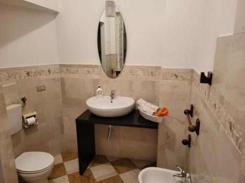 bagno con lavandino, servizi igienici e specchio di Appartamento Reale ad Alessandria