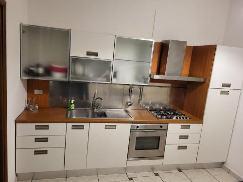a kitchen with white cabinets and stainless steel appliances at Appartamento Reale in Alessandria