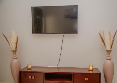 ein Wohnzimmer mit 2 Vasen und einem TV in der Unterkunft Sisi's Homes in Arusha