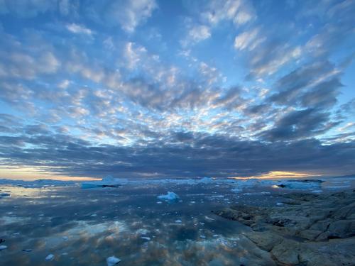 a cloudy sky with rocks in the water at Illu Rental - Grand seaview vacation house in Ilulissat