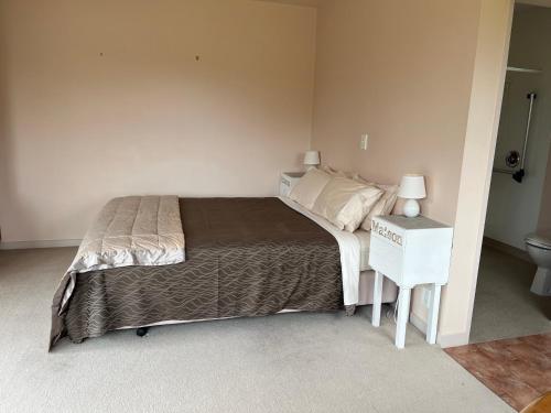 um quarto com uma cama e uma mesa de cabeceira com uma cama sidx sidx sidx sidx em Carrickfergus Cottage Unit 1 em Harihari
