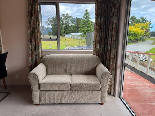 a couch sitting in front of a large window at Carrickfergus Cottage Unit 1 in Harihari
