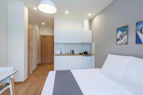 a white bedroom with a white bed and a kitchen at Dialog Kokhta in Bakuriani