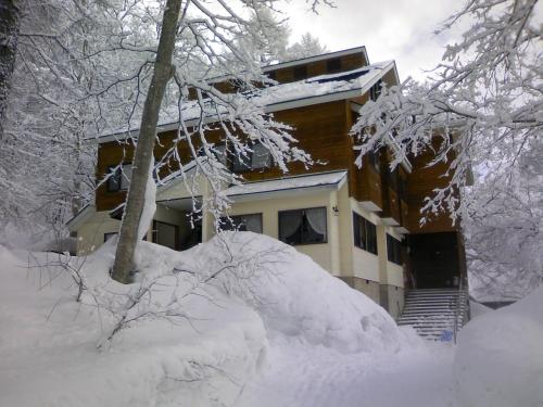 ein Haus mit einem Stapel Schnee davor in der Unterkunft ペンションヴォルケ in Shinano