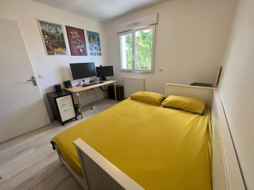 1 dormitorio con cama amarilla y escritorio en Maison moderne à 25 minutes du centre Paris et JO 2024, en Eaubonne
