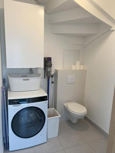 une salle de bain avec machine à laver et toilettes dans l'établissement Maison moderne à 25 minutes du centre Paris et JO 2024, à Eaubonne