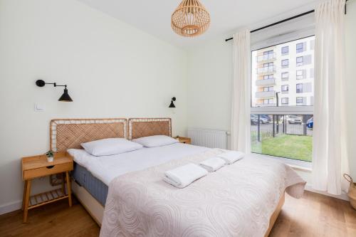 a bedroom with a bed with white sheets and a window at Letnicka Cosy Apartment with Garden in Gdańsk