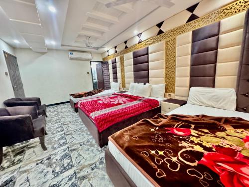una habitación de hotel con 2 camas y una silla en Royal Blue inn Hotel en Islamabad
