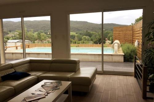 - un salon avec un canapé et une piscine dans l'établissement A l'ombre du Saule. Villa 10 personnes + piscine, à Saint-Romain-en-Viennois