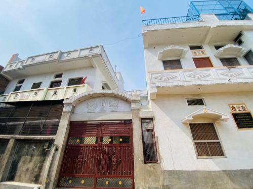 un edificio con una porta rossa accanto a un altro edificio di The Narayan Bhawan , ramanuj ashram ,haridas nagar ,ramkot ayodhya ji a Ayodhya