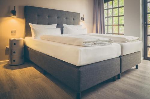 een slaapkamer met een groot bed met witte lakens bij rugs HOTEL Köln in Keulen