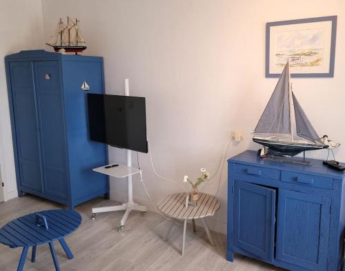 Cette chambre dispose d'une armoire bleue avec une télévision et un bateau à jouets. dans l'établissement La goélette - Les Gîtes de la Côte d'Amour, au Croisic