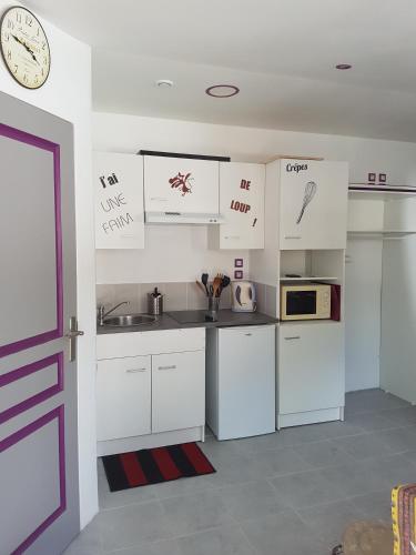 eine Küche mit weißen Schränken und einer Uhr an der Wand in der Unterkunft Chelles-Max01 in Chelles