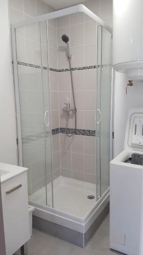 une douche avec une porte vitrée dans une salle de bain dans l'établissement Chelles-Max01, à Chelles
