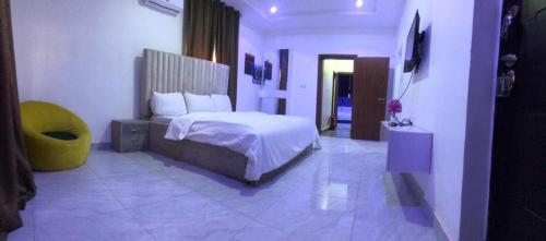 1 dormitorio con 1 cama y 1 silla amarilla en Carolina Apartments Wuye, en Abuja