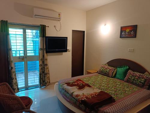 a bedroom with a bed and a tv and a window at Blue Diamond Guest House in Pune