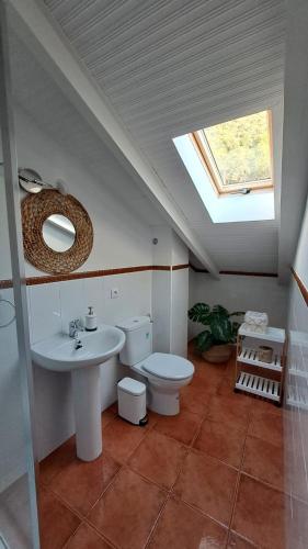a bathroom with a toilet and a sink and a skylight at LA CRUZ DE LA ATALAYA in Benamahoma