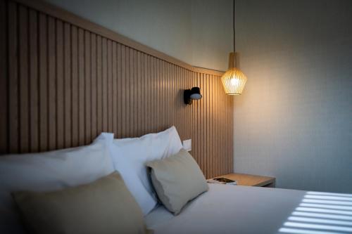 a bedroom with a bed with white pillows and a lamp at MH Apartments Urban in Barcelona
