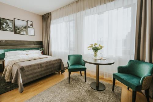 a bedroom with a bed and two chairs and a table at Green Hotel in Inowrocław