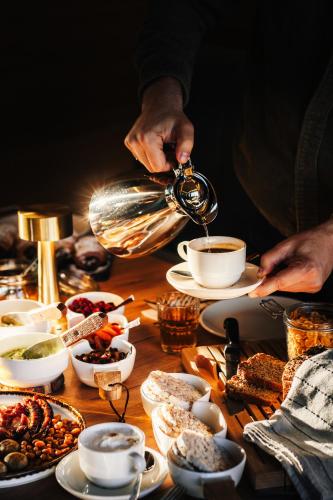 a person pouring coffee into a cup on a table at Green Hotel in Inowrocław