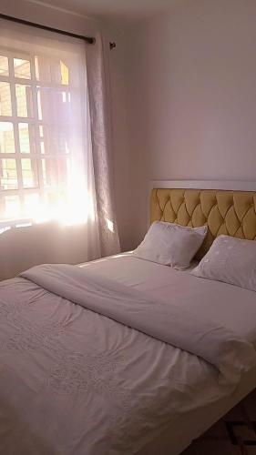 a bedroom with a large white bed with a window at Serene Safaris Airbnb in Thika in Thika