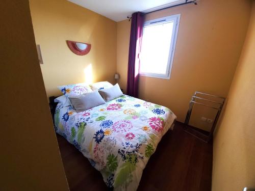 een slaapkamer met een bed met een bloemdekbed en een raam bij La villa d'Evalou in Calvisson