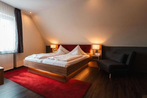 - une chambre avec un grand lit et une chaise dans l'établissement Landhotel und Weingasthof Schwarzer Adler, à Wiesenbronn
