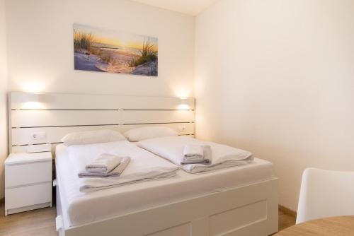 a white bed in a room with a painting on the wall at Feriendorf Slawitsch in Bad Sulza