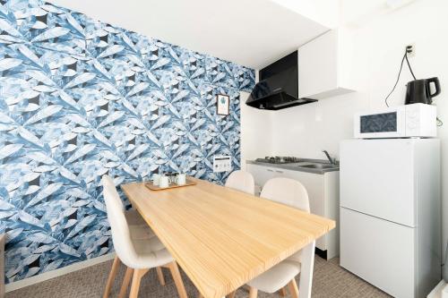 une cuisine et une salle à manger avec une table et des chaises en bois dans l'établissement ILIMA Higashi Nakano 新宿から電車で5分 東中野駅まで徒歩2分 最大4人 洗濯機 ダイニングキッチン 電子レンジ, à Tokyo