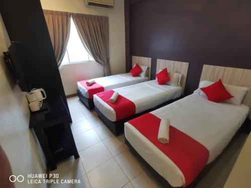 a hotel room with two beds with red pillows at FERRINGHI PARADISE HOTEL in Batu Ferringhi