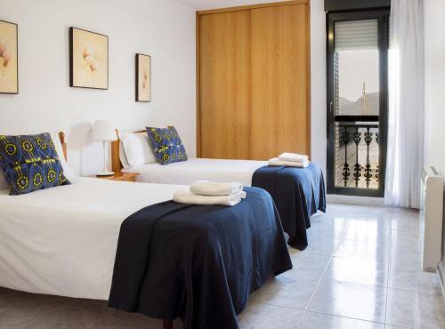 two beds in a hotel room with towels on them at Apartamentos Salceda in Noja