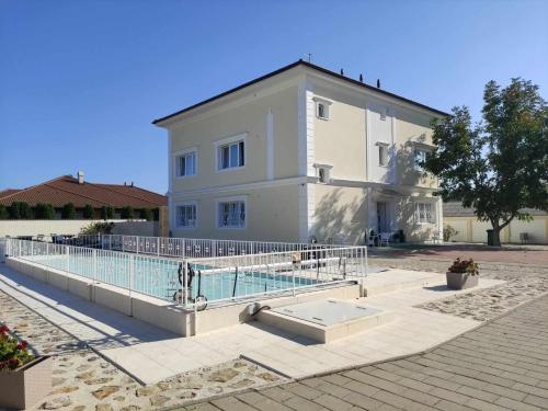 a large white building with a pool in front of it at Kemence Csárda és Szálloda in Nyíregyháza