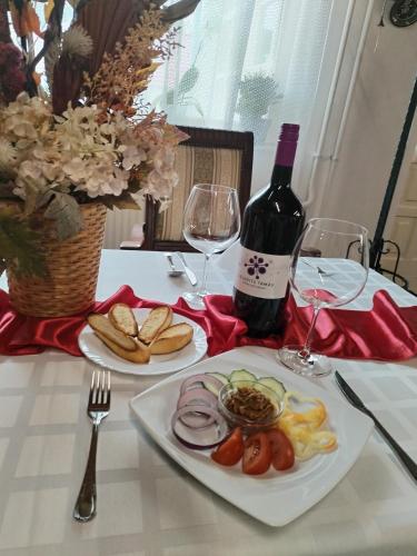 a table with a plate of food and a bottle of wine at Kemence Csárda és Szálloda in Nyíregyháza