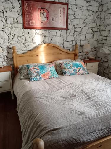 a bed in a bedroom with a stone wall at Gite Les Volets Bleus du Segur in Le Ségur-Suech