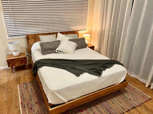 1 dormitorio con 1 cama con sábanas y almohadas blancas en Tranquil holiday home on the water’s edge. en Rainbow Beach