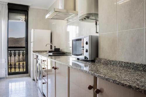 a kitchen with a counter with a microwave and a refrigerator at Apartamentos Salceda in Noja