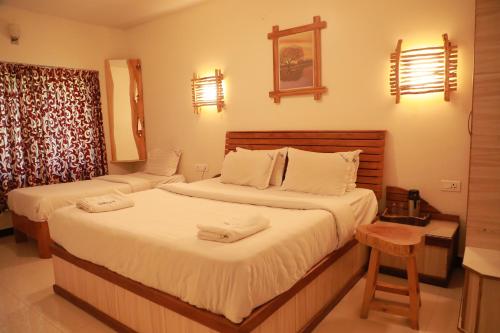 um quarto de hotel com duas camas e uma mesa em The Woodlands Residency- Unmarried and stag groups not allowed em Ooty