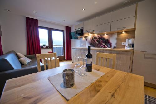 a kitchen with a wooden table with a bottle of wine on it at Haus Sonnwend in Ellmau